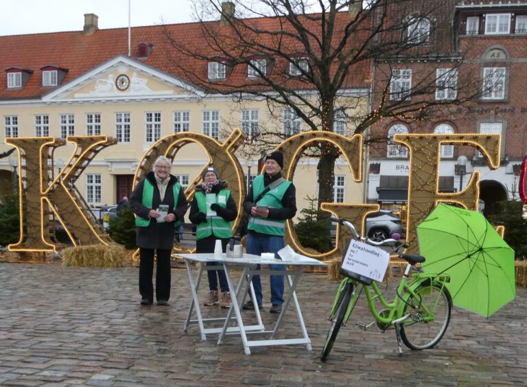 Tre bedsteforældre og en grøn cykel og grøn paraply på Køge Torv