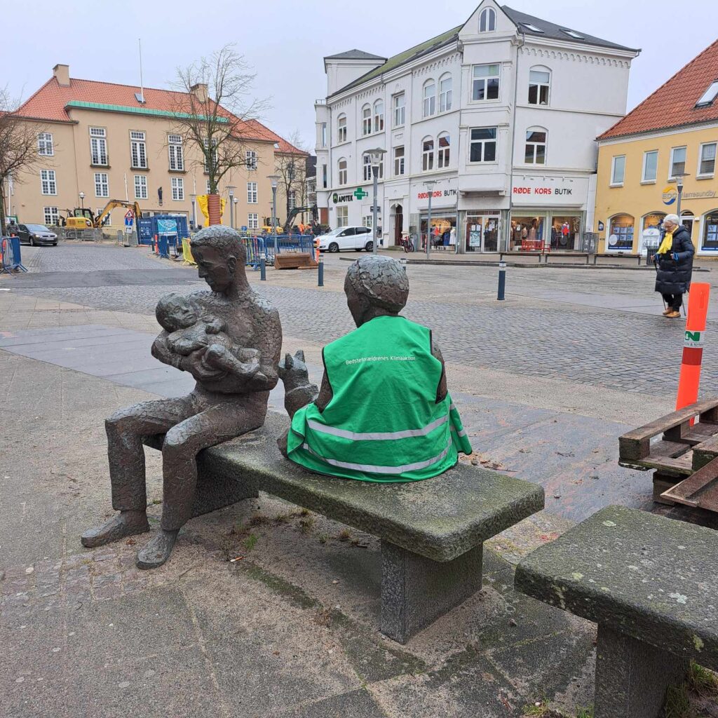 Skulptur på Nørresundby Torv iklædt en grøn BKA vest